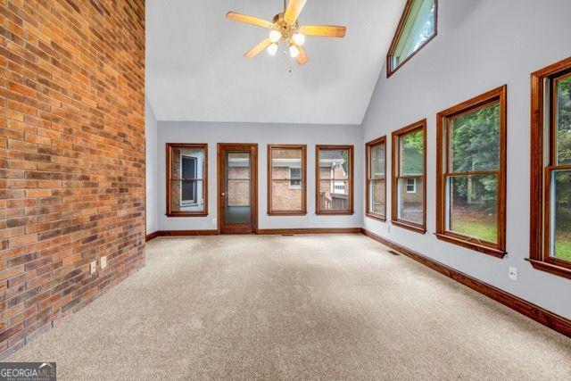 362 Clyde Ct, Mcdonough, GA 30252 - unfurnished room featuring carpet, healthy amount of natural light, baseboards, high vaulted ceiling, and brick wall