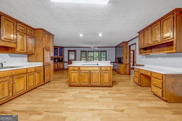 362 Clyde Ct, Mcdonough, GA 30252 - kitchen featuring a sink, brown cabinets, a kitchen island, light wood-style floors, and a textured ceiling