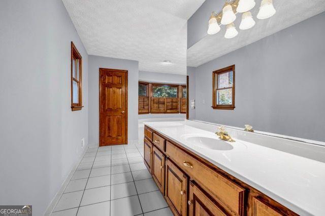 362 Clyde Ct, Mcdonough, GA 30252 - bathroom featuring vanity, tile patterned flooring, a textured ceiling, and a chandelier