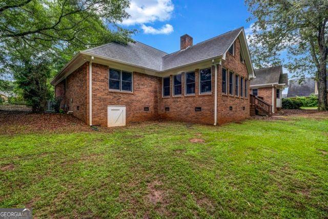 362 Clyde Ct, Mcdonough, GA 30252 - back of property featuring crawl space, a chimney, a lawn, and brick siding