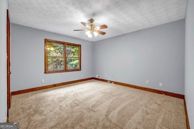 362 Clyde Ct, Mcdonough, GA 30252 - carpeted spare room featuring ceiling fan, baseboards, and a textured ceiling