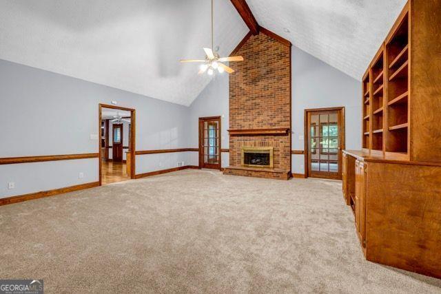 362 Clyde Ct, Mcdonough, GA 30252 - unfurnished living room with ceiling fan, high vaulted ceiling, a brick fireplace, light carpet, and baseboards