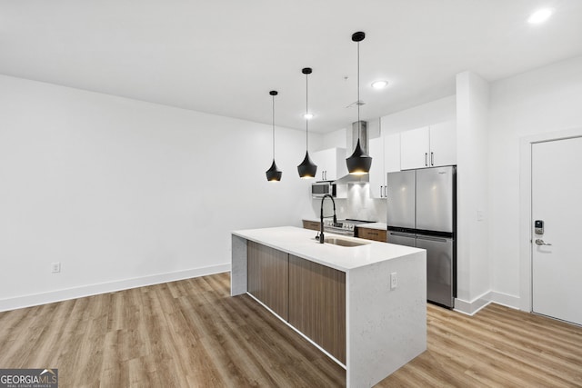 112 Rogers St NE Unit 304, Atlanta, GA 30317 - kitchen with appliances with stainless steel finishes, wall chimney range hood, light wood-type flooring, an island with sink, and white cabinets