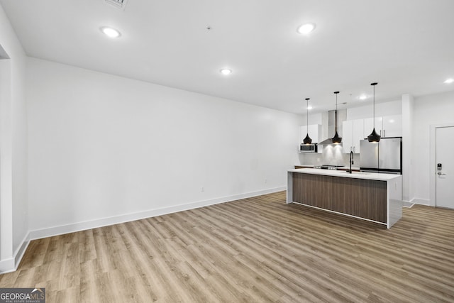 112 Rogers St NE Unit 304, Atlanta, GA 30317 - kitchen with wall chimney range hood, light wood finished floors, recessed lighting, a kitchen island with sink, and light countertops