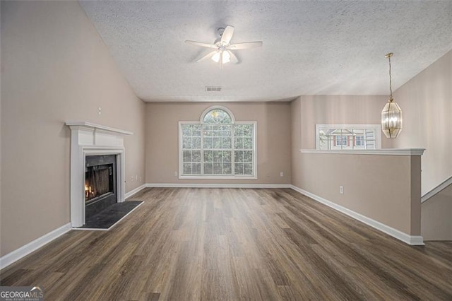 1501 Buckingham Pl, Stockbridge, GA 30281 - unfurnished living room with wood finished floors, a textured ceiling, a warm lit fireplace, ceiling fan, and a chandelier