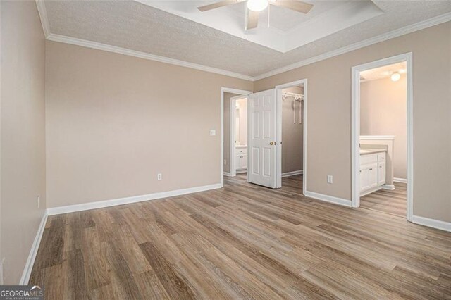 1501 Buckingham Pl, Stockbridge, GA 30281 - unfurnished bedroom featuring a spacious closet, light wood-style floors, a closet, ensuite bathroom, and ornamental molding