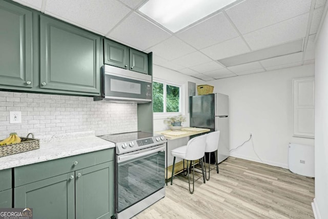 5421 Amherst Way, Flowery Branch, GA 30542 - kitchen with appliances with stainless steel finishes, green cabinetry, backsplash, light wood-style floors, and a paneled ceiling