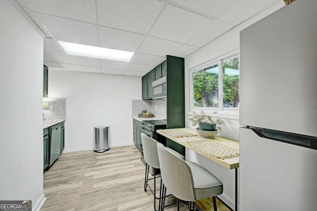 5421 Amherst Way, Flowery Branch, GA 30542 - kitchen with stainless steel appliances, green cabinetry, a paneled ceiling, light countertops, and backsplash
