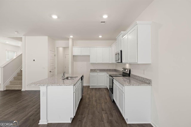 12085 Conrad Cir, Hampton, GA 30228 - kitchen featuring appliances with stainless steel finishes, white cabinetry, light stone counters, dark wood-type flooring, and a center island with sink