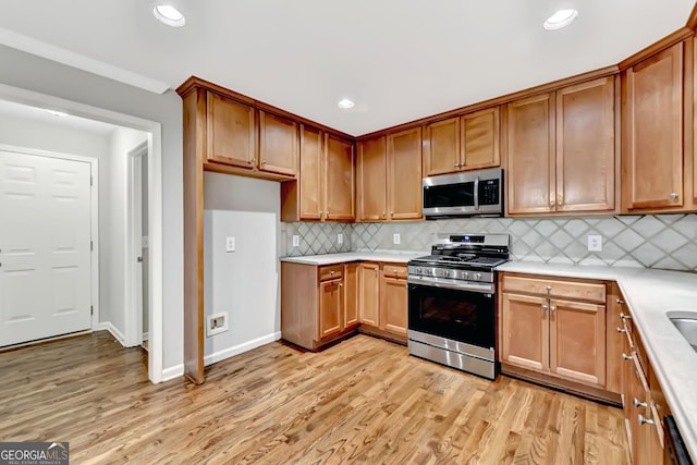327 Oakland Bay Ct, Loganville, GA 30052 - kitchen with appliances with stainless steel finishes, light countertops, light wood-type flooring, decorative backsplash, and recessed lighting