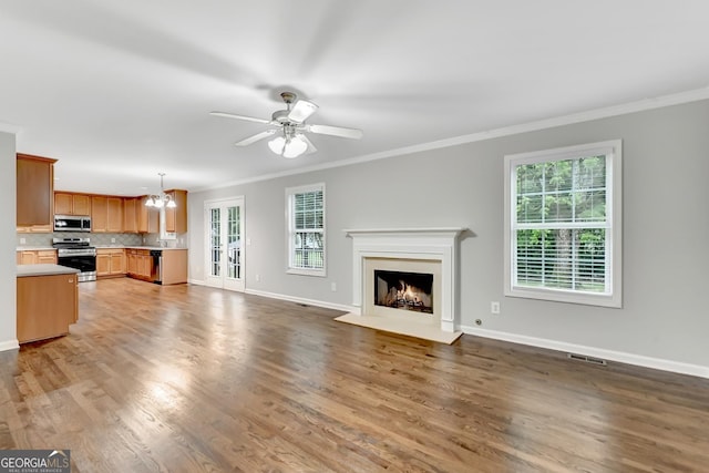327 Oakland Bay Ct, Loganville, GA 30052 - unfurnished living room with crown molding, baseboards, a chandelier, a ceiling fan, and wood finished floors