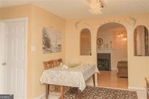 1405 Overland Xing, Alpharetta, GA 30004 - dining space with arched walkways, a fireplace, baseboards, and wood finished floors