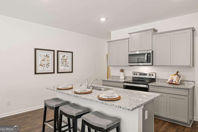 1311 Aura Ln, Lawrenceville, GA 30045 - kitchen featuring stainless steel appliances, gray cabinetry, a center island with sink, light stone counters, and recessed lighting