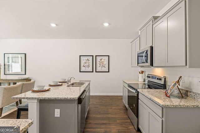 1311 Aura Ln, Lawrenceville, GA 30045 - kitchen with appliances with stainless steel finishes, gray cabinetry, dark wood-style floors, a breakfast bar, and light stone counters