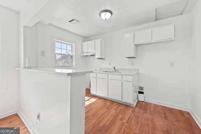 2110 Newnan St, Atlanta, GA 30344 - kitchen featuring under cabinet range hood, white cabinetry, light wood-style floors, and light countertops