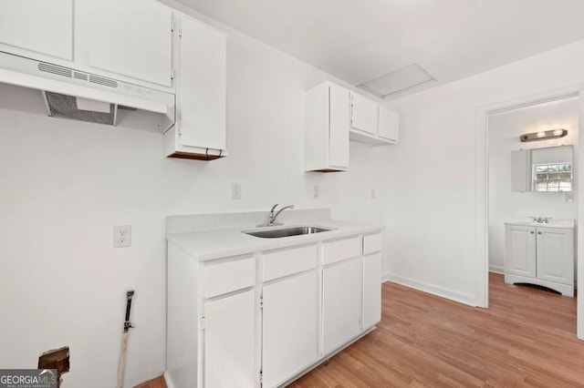 2110 Newnan St, Atlanta, GA 30344 - kitchen with light countertops, white cabinets, and light wood finished floors