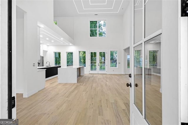 2764 Midway Rd, Decatur, GA 30030 - unfurnished living room with light wood-style flooring, a towering ceiling, french doors, and a sink