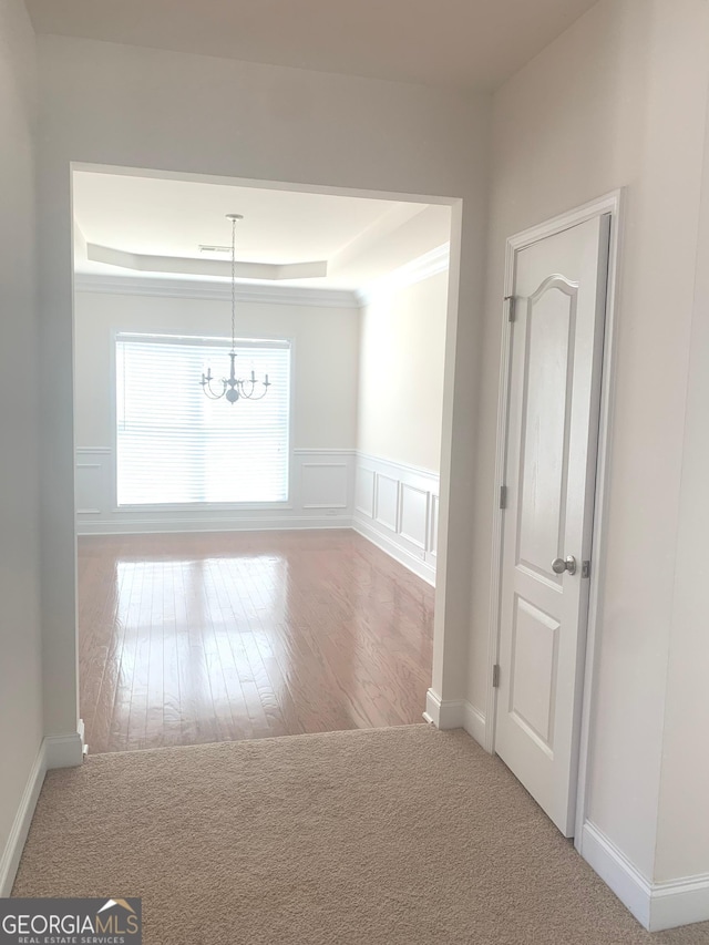 2118 Water Mill Ct, Buford, GA 30519 - corridor with a chandelier, a tray ceiling, hardwood / wood-style flooring, baseboards, and wainscoting