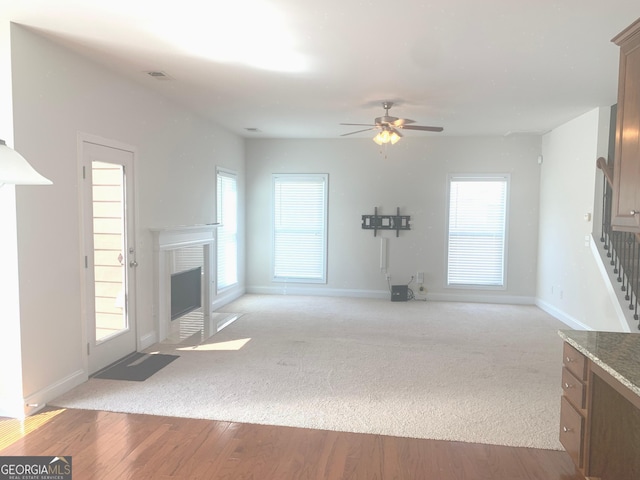 2118 Water Mill Ct, Buford, GA 30519 - unfurnished living room featuring a ceiling fan, baseboards, a fireplace with flush hearth, stairway, and light carpet