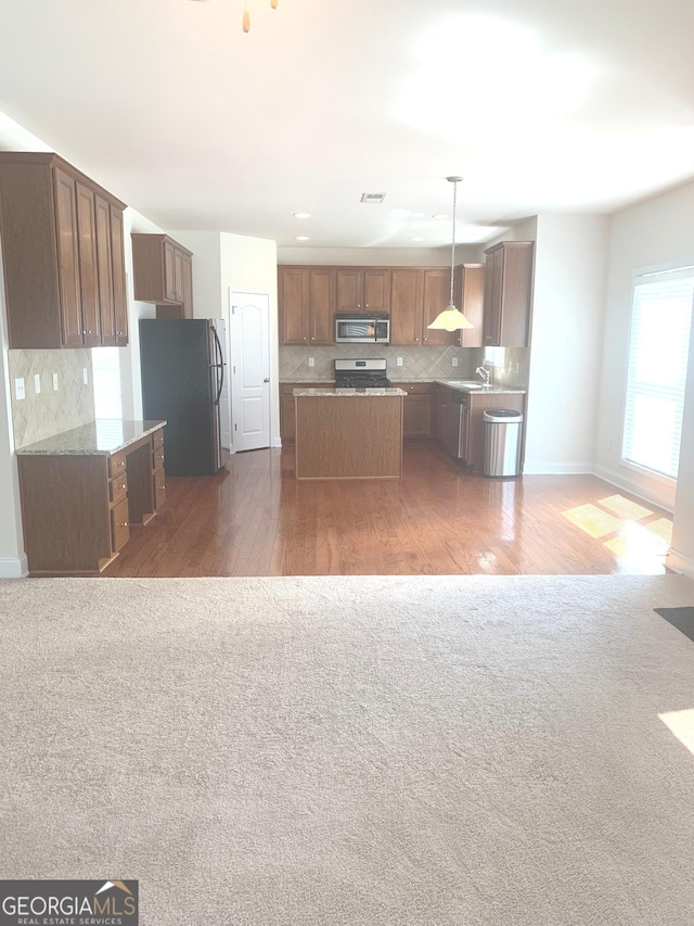 2118 Water Mill Ct, Buford, GA 30519 - kitchen featuring appliances with stainless steel finishes, a kitchen island, tasteful backsplash, dark colored carpet, and open floor plan