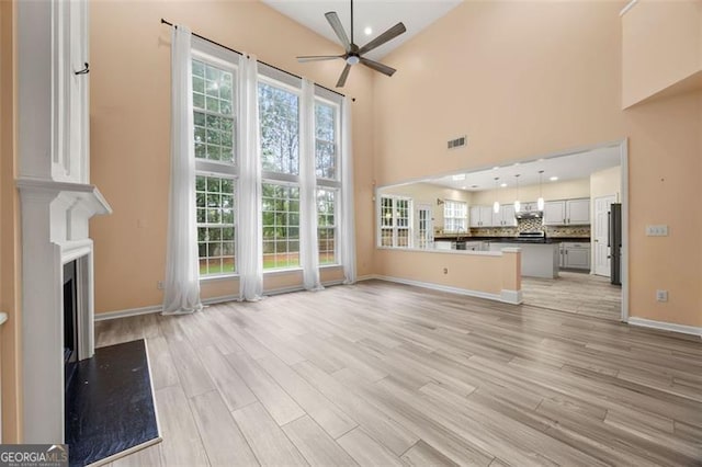 5156 Amberden Hall Dr, Suwanee, GA 30024 - unfurnished living room featuring ceiling fan, light wood-style flooring, a towering ceiling, a fireplace, and recessed lighting