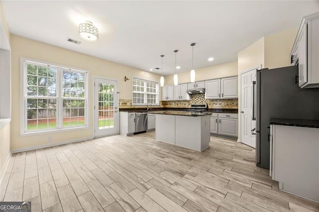 5156 Amberden Hall Dr, Suwanee, GA 30024 - kitchen featuring dark countertops, stainless steel appliances, under cabinet range hood, light wood-style flooring, and healthy amount of natural light