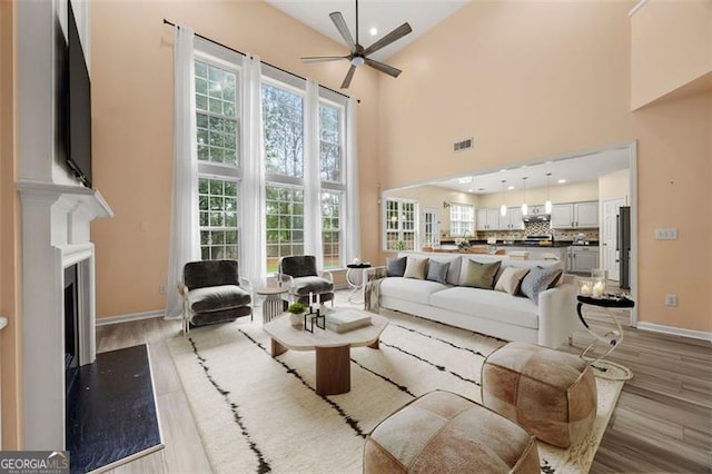 5156 Amberden Hall Dr, Suwanee, GA 30024 - living area featuring a towering ceiling, ceiling fan, light wood-style floors, a fireplace with flush hearth, and recessed lighting