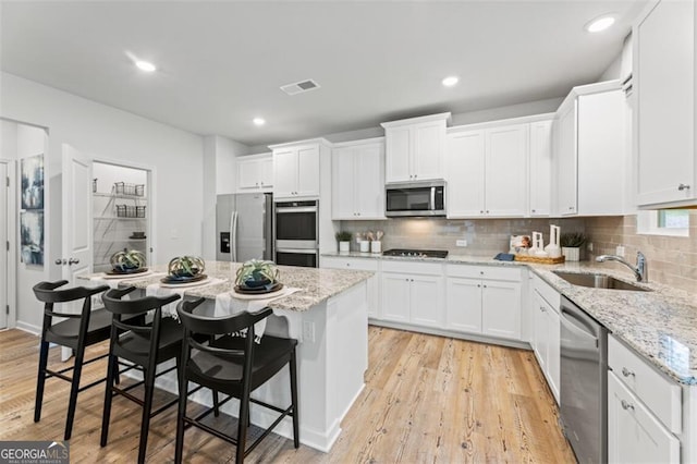 817 Dobby Way Lot 96, Mcdonough, GA 30252 - kitchen featuring stainless steel appliances, a sink, white cabinets, a kitchen island, and a kitchen bar