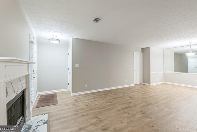1005 Peachtree Forest Ter, Peachtree Corners, GA 30092 - unfurnished living room with light wood-style floors, a high end fireplace, a textured ceiling, and baseboards