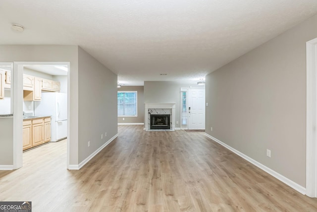 1005 Peachtree Forest Ter, Peachtree Corners, GA 30092 - unfurnished living room featuring light wood-style flooring, a fireplace, baseboards, and a textured ceiling