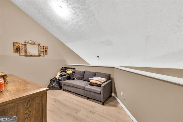 6504 Samoa, Flowery Branch, GA 30542 - living area featuring light wood finished floors, vaulted ceiling, and a textured ceiling