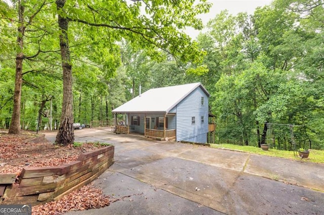 6504 Samoa, Flowery Branch, GA 30542 - garage with a porch, concrete driveway, and a wooded view