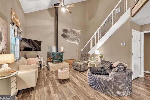 6504 Samoa, Flowery Branch, GA 30542 - living area featuring wood finished floors, a high ceiling, stairs, ceiling fan, and a wood stove