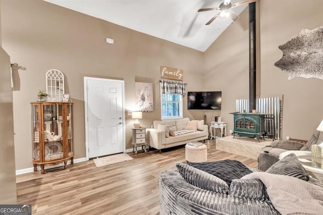 6504 Samoa, Flowery Branch, GA 30542 - living area featuring high vaulted ceiling, a ceiling fan, a wood stove, light wood finished floors, and baseboards