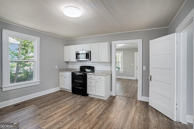 930 W Broad St, Griffin, GA 30223 - kitchen with black range with electric stovetop, stainless steel microwave, white cabinets, dark wood-style flooring, and baseboards