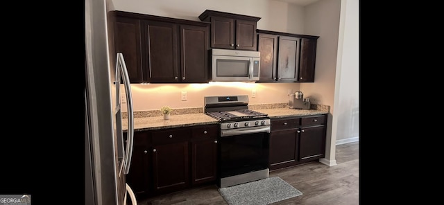 4241 Swamp Cypress Trl, Gainesville, GA 30504 - kitchen featuring appliances with stainless steel finishes, light stone counters, dark brown cabinets, and wood finished floors