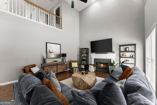 1504 Oglethorpe Dr, Suwanee, GA 30024 - living room featuring a high ceiling, wood finished floors, a glass covered fireplace, and ceiling fan