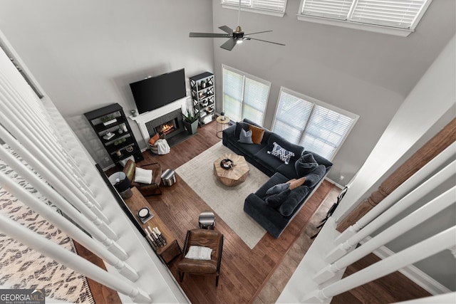 1504 Oglethorpe Dr, Suwanee, GA 30024 - living area with wood finished floors, a warm lit fireplace, a ceiling fan, and a towering ceiling