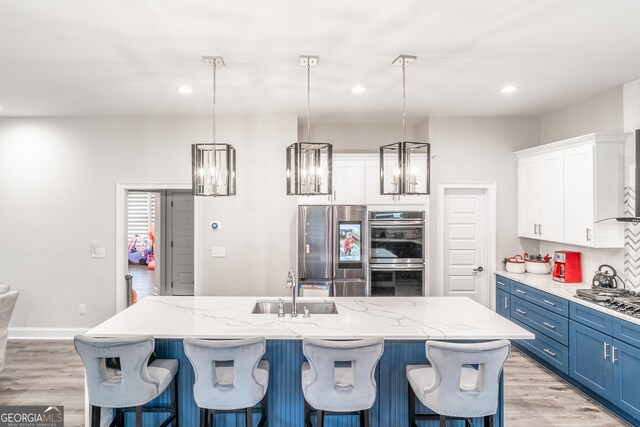 5490 Bent Grass Way, Douglasville, GA 30135 - kitchen with appliances with stainless steel finishes, white cabinetry, blue cabinets, light wood-style flooring, and a breakfast bar
