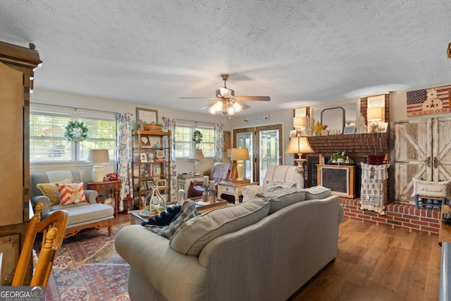 118 Duvall Dr, Stockbridge, GA 30281 - living area with wood finished floors, a ceiling fan, a textured ceiling, and a brick fireplace