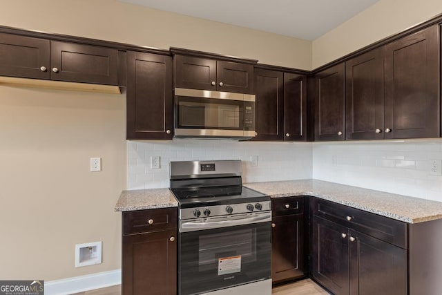 123 Oak Rd, Locust Grove, GA 30248 - kitchen with appliances with stainless steel finishes, light stone counters, dark brown cabinetry, backsplash, and baseboards