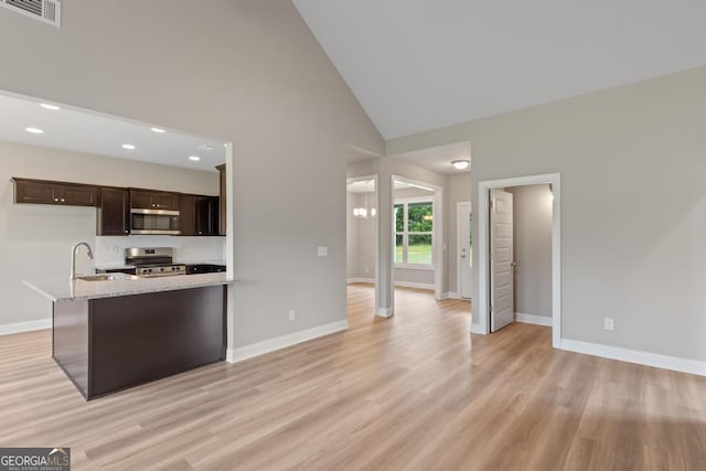 123 Oak Rd, Locust Grove, GA 30248 - kitchen with stainless steel appliances, dark brown cabinetry, light stone counters, baseboards, and high vaulted ceiling