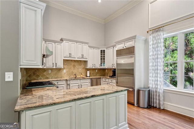 3280 Stillhouse Ln SE Unit 410, Atlanta, GA 30339 - kitchen featuring appliances with stainless steel finishes, a peninsula, light stone counters, tasteful backsplash, and crown molding