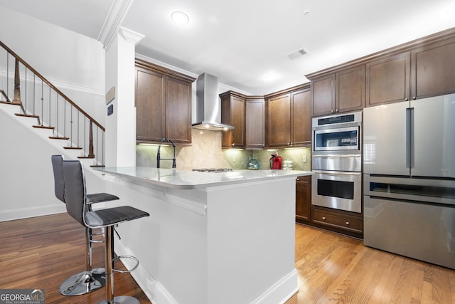 3280 Stillhouse Ln SE Unit 410, Atlanta, GA 30339 - kitchen featuring stainless steel appliances, wall chimney exhaust hood, light wood-type flooring, a breakfast bar, and recessed lighting