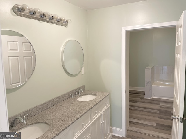 3433 Sandra Fay Dr, Macon, GA 31206 - full bath with double vanity, wood finished floors, a garden tub, and baseboards