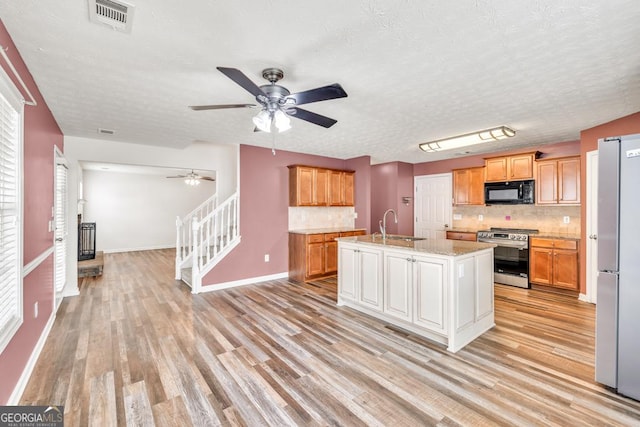 3338 Gardenside Walk, Loganville, GA 30052 - kitchen featuring appliances with stainless steel finishes, ceiling fan, backsplash, light wood finished floors, and a textured ceiling