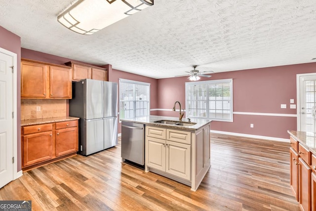 3338 Gardenside Walk, Loganville, GA 30052 - kitchen featuring appliances with stainless steel finishes, a ceiling fan, light wood-style flooring, light stone countertops, and a textured ceiling
