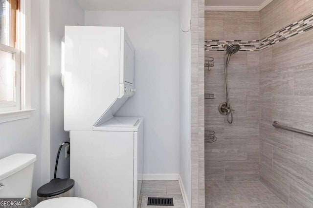 935 Old Loganville Rd, Loganville, GA 30052 - full bath featuring stacked washer and clothes dryer, tiled shower, and ornamental molding