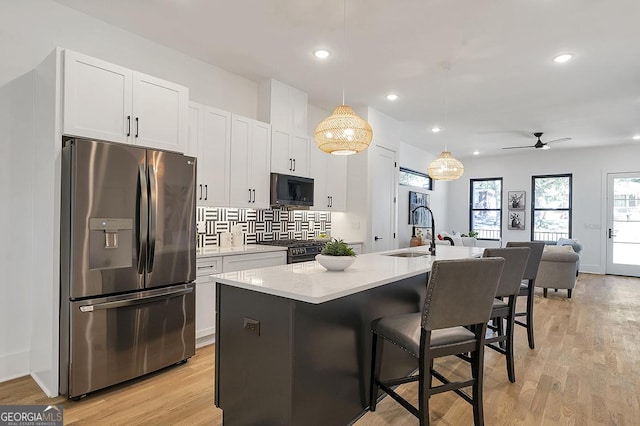 1464 Ezra Church Dr NW, Atlanta, GA 30314 - kitchen with black appliances, a sink, a center island with sink, white cabinetry, and a kitchen bar