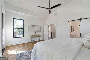 1464 Ezra Church Dr NW, Atlanta, GA 30314 - bedroom featuring a barn door, wood finished floors, baseboards, and lofted ceiling